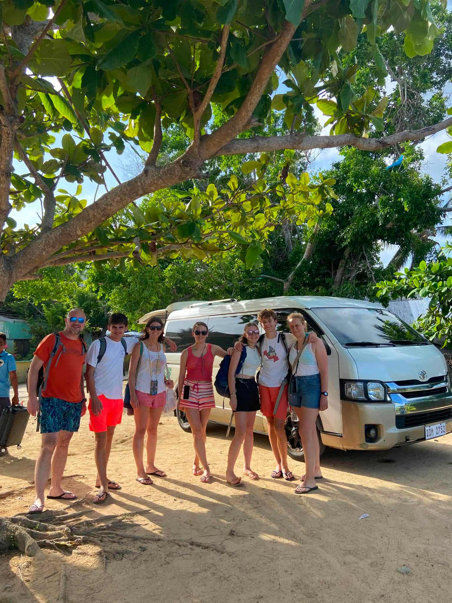 Group of seven guests standing with their private Toyota Hiace van in Palawan